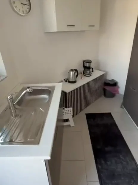 Küche mit Spüle, Kaffeemaschine, Wasserkocher und Hängeschränken