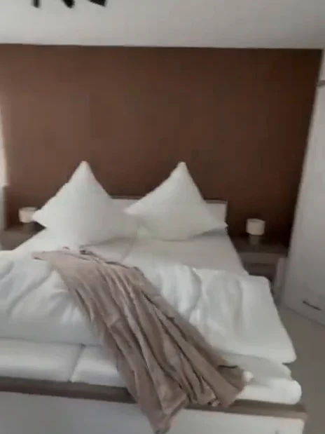 Schlafzimmer mit Doppelbett vor der Holzpaneel-Akzentwand